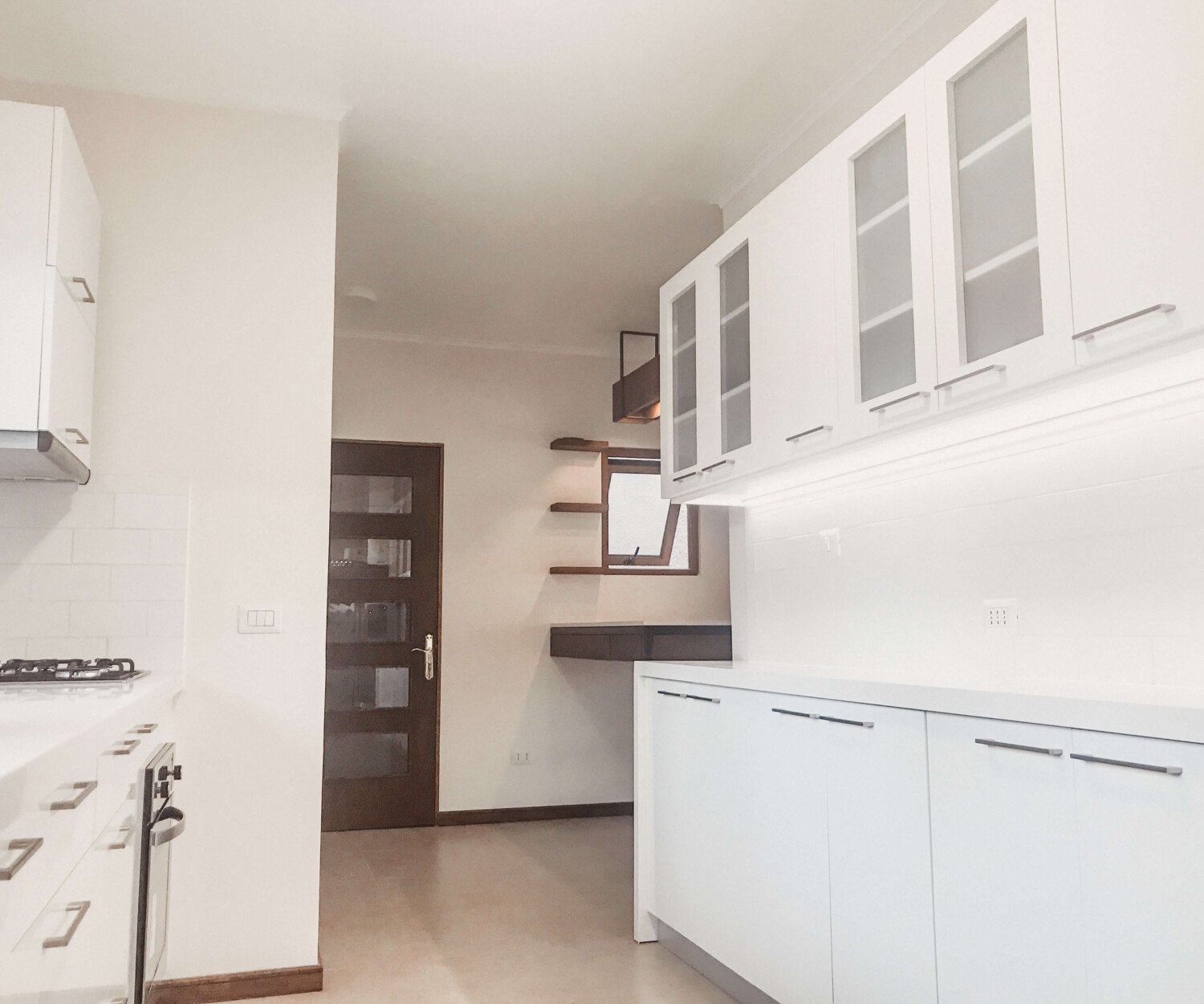 Cocina en L de Casa Porter en blanco con repisas de madera oscura